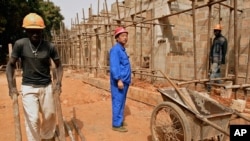 FILE - A Chinese foreman looks on as laborers work on the construction of military officers housing, donated by China, in Bissau, Guinea-Bissau, Jan. 3, 2007. 