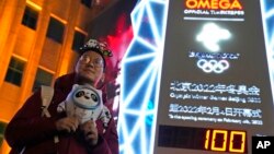 A supporter of the 2022 Beijing Winter Olympics poses for photos with a countdown clock as it crosses into the 100 days countdown to the opening of the Winter Olympics in Beijing, China, Oct. 26, 2021.