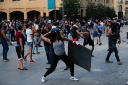 People throw stones during a protest following the recent explosion that killed many and devastated the city, in Beirut, Lebanon, Aug. 11, 2020.