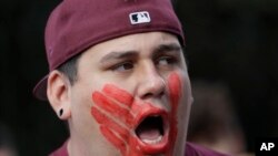 FILE - William Red Bear wears a red hand print image on his face as he marches in support of missing and murdered indigenous women during a rally to mark Indigenous Peoples' Day in downtown Seattle, Washington, Oct. 14, 2019. 