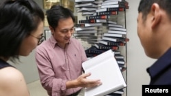 FILE - Scientist He Jiankui shows "The Human Genome", a book he edited, at his company Direct Genomics in Shenzhen, Guangdong province, China, Aug. 4, 2016. 