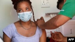 A woman is vaccinated by a member of the Western Cape Metro EMS in an ambulance at a COVID-19 vaccination event in Manenberg, in Cape Town, South Africa, Dec. 8, 2021.