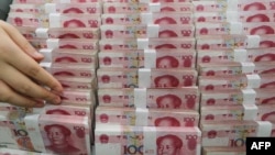 A teller counts yuan banknotes in a bank in Lianyungang, east China's Jiangsu province on August 11, 2015. 