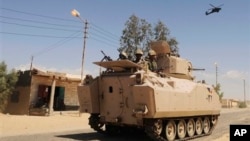 Egyptian Army soldiers in armored personnel carriers and a helicopter gunship patrol through a village in the northern Sinai Sept. 7, 2013.