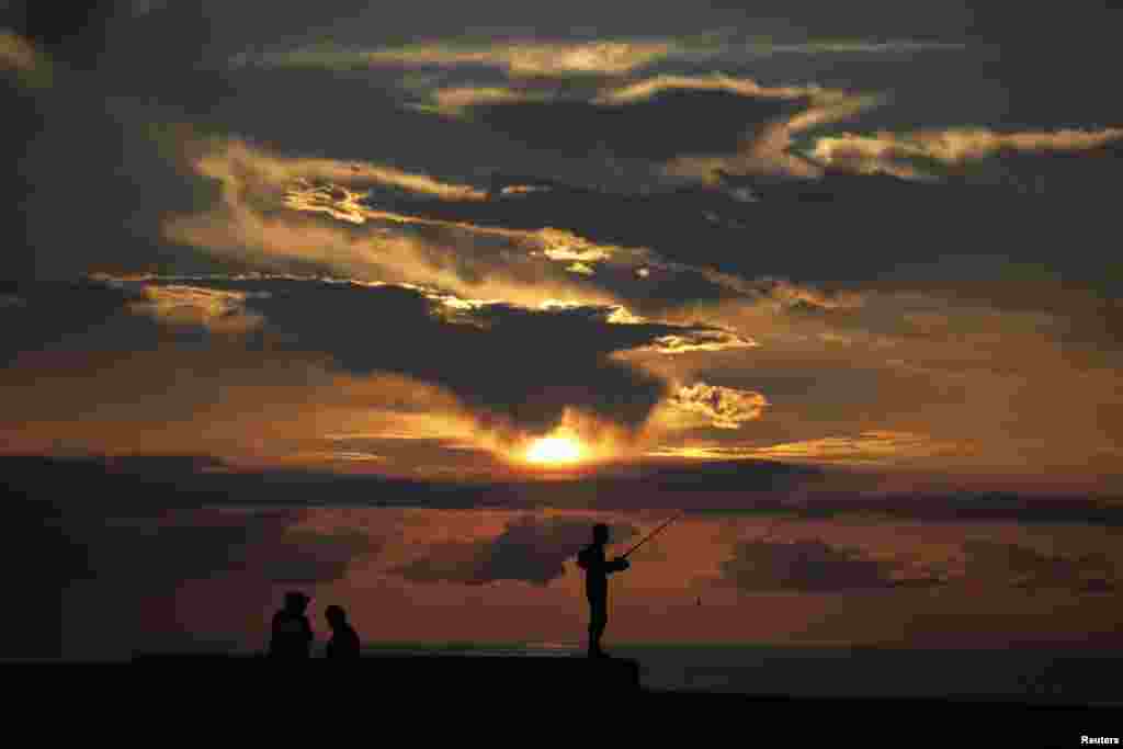 Seorang nelayan menarik pancingnya seiring terbenamnya matahari di tepi laut &#39;El Malecon&#39;, Havana, Kuba, 1 Agustus 2013.