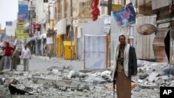 A Shiite fighter known as a Houthi stands guard in front of buildings destroyed by a Saudi-led airstrike in Sana'a, Sept. 5, 2015. 