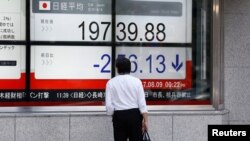 A man looks at an electronic board showing Japan's Nikkei average outside a brokerage at a business district in Tokyo, Aug. 9, 2017. 