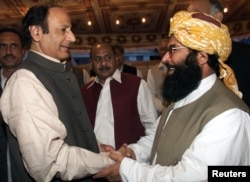 FILE - JUI-F Secretary General Abdul Ghafoor Haidari, right, greets Chaudhry Shujaat Hussein, parliamentary leader of the pro-military Pakistan Muslim League Quaid-e-Azam, at a reception hosted by PML-QA in Islamabad, Nov. 7, 2002.
