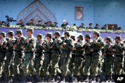FILE - Iran's President Hassan Rouhani, top center, reviews army troops marching during the 37th anniversary of Iraq's 1980 invasion of Iran, in front of the shrine of the late revolutionary founder, Ayatollah Khomeini, just outside Tehran, Iran.