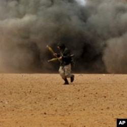 Libyan rebel fighters run for cover as shells explode nearby during a battle with forces loyal to leader Moammer Gadhafi, just few kilometers outside the oil town of Ras Lanuf, March 9, 2011