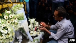 A Bangladeshi social activist lights a candle on floral arrangement that he placed on a road block leading to the Holey Artisan Bakery, the scene of a fatal attack and siege, in Dhaka on July 3, 2016.