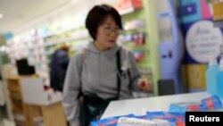 Protection class FFP2 respirator masks are seen inside a pharmacy as a tourist looks at them, amid the novel coronavirus outbreak, in Barcelona, Spain, Feb. 4, 2020.