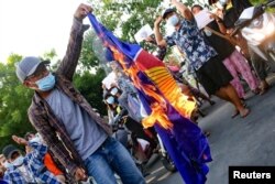 Para pengunjuk rasa menentang junta Myanmar dengan membakar bendera Perhimpunan Bangsa-Bangsa Asia Tenggara, di Mandalay, Myanmar, 5 Juni 2021. (Foto: Reuters)
