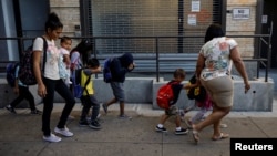 Children cover their faces as they are escorted to the Cayuga Center, which provides foster care and other services to immigrant children separated from their families, in New York City, July 10, 2018. 