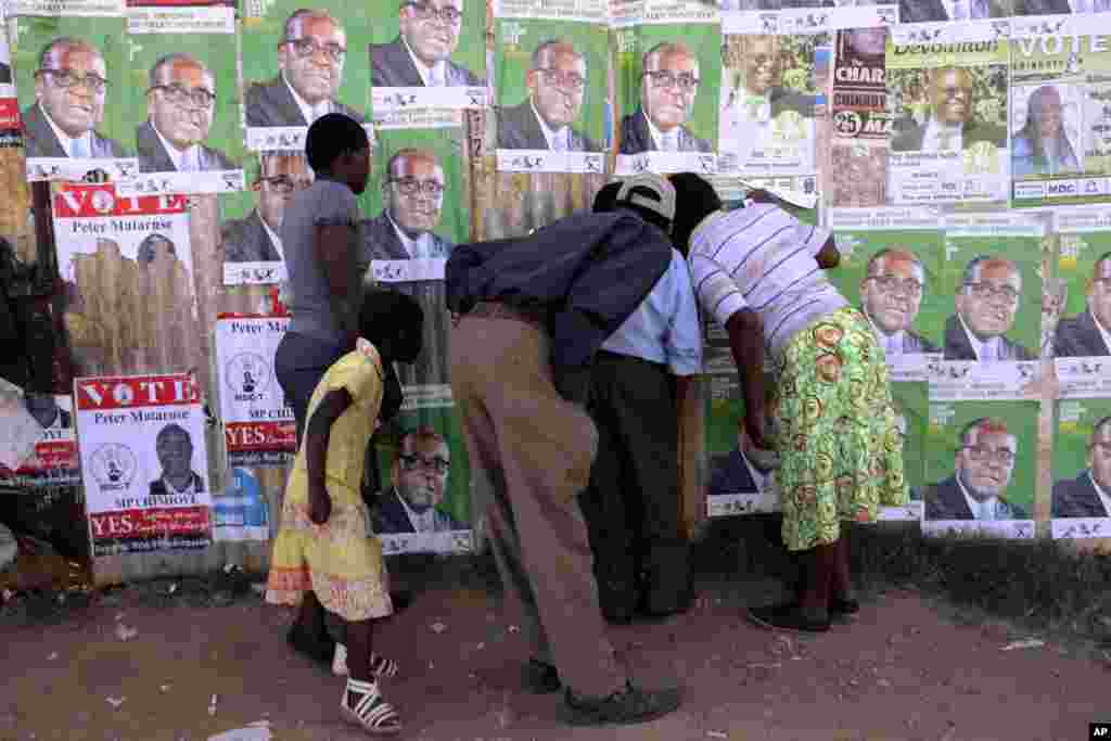 Residents of Epworth peep through a hole while watching a street performance a day before elections, Harare, July, 30, 2013.