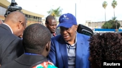 Uhuru Kenyatta (C) arrives at the Jomo Kenyatta International Airport as he departs to attend a hearing at the International Criminal Court at The Hague, in Nairobi, October 7, 2014.