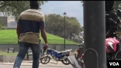 An armed, masked off-duty policeman holds a gun as he walks on the street during a gunfight between policemen and members of the army, in Haiti, Feb. 23, 2020. (Matiado Vilme/VOA Creole)