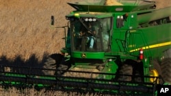 FILE - A farmer uses a combine to harvest his soybean field Oct. 21, 2014, in Loami, Ill.