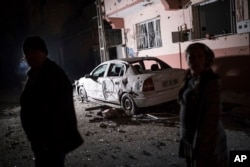 People look at the damage caused by a rocket fired by suspected Syrian Kurdish fighters from Syria, across the border, into the town of Kilis, Turkey, early Jan. 21, 2018. According to the local governor four rockets struck the town, hitting two houses and an office, injuring one person.