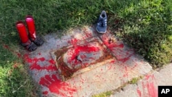 Red painted handprints cover the empty spot at a park in Albuquerque, New Mexico, on Thursday, July 1, 2021, where a historical marker for the Indigenous children who died while attending a boarding school nearby was removed. 