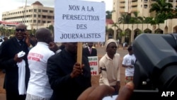 FILE - A Cameroonian journalist holds a sign raeding "No to the persecution of journalists" during a free speech rally in Yaounde, Cameroon, May 3, 2010. 
