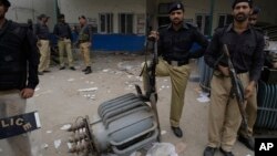 FILE - Pakistani police officers stand guard at the office of local electrical company attacked by angry protesters to condemn electricity shortages in Lahore, Pakistan, March 27, 2012. 