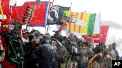 FILE - In this Dec. 5, 2016, file photo, military veterans and Native American tribal elders come to a stop for a ceremonial prayer during a march to a closed bridge across from the Dakota Access oil pipeline site in Cannon Ball, N.D.