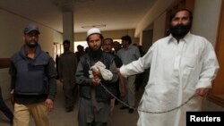 FILE - Police escort a man, identified as Afghan Taliban's top military commander, Mullah Abdul Ghani Baradar.