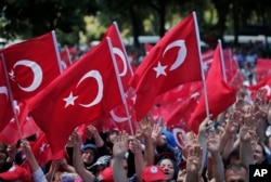FILE - Pro-government demonstrators wave Turkish flags as they protest against the attempted coup in Istanbul, Turkey, July 19, 2016.
