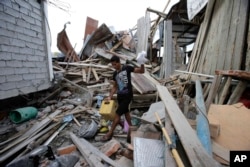 A man, whose wife and unborn son were killed during a 7.8-magnitude earthquake, recovers belongings from his collapsed home, in La Chorrera, Ecuador, April 18, 2016.