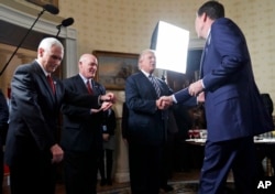FILE - Vice President Mike Pence, left, and Secret Service Director Joseph Clancy stand as President Donald Trump shakes hands with FBI Director James Comey during a reception for inaugural law enforcement officers and first responders in the Blue Room of