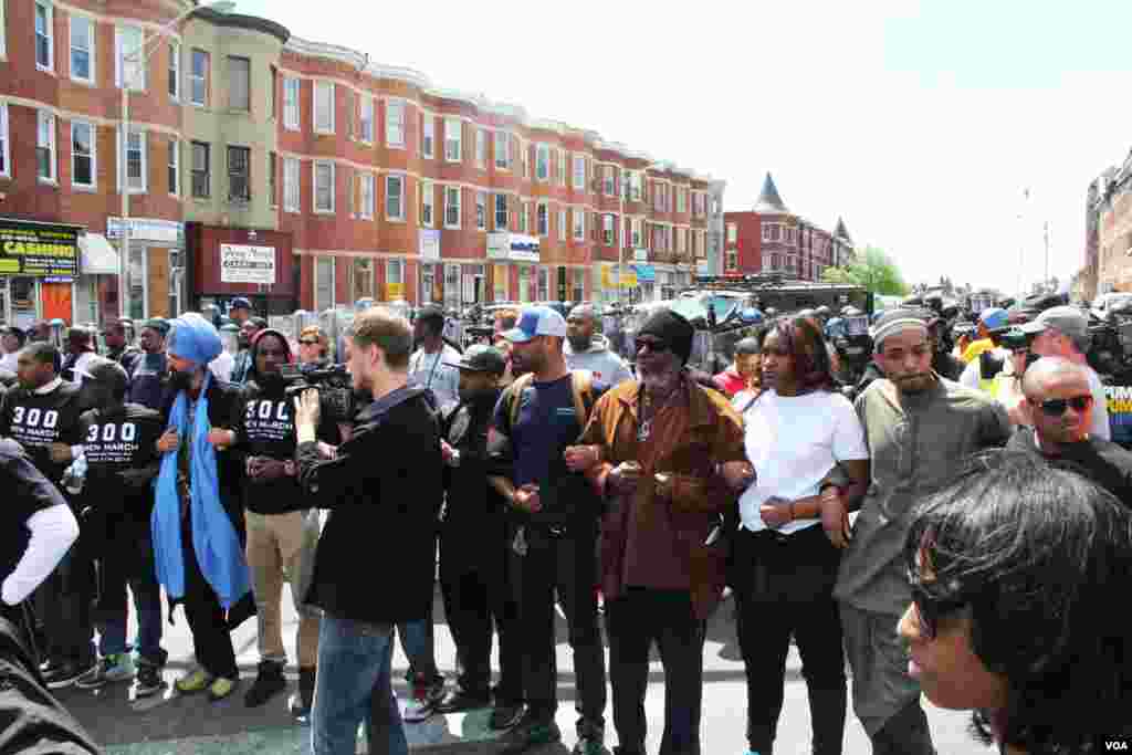 Polisi Baltimore merespon sebentar dengan cairan merica sebelum warga sipil bergandengan tangan membentuk dua rantai paralel antara demonstran yang rusuh dan polisi (28/4). (VOA/Victoria Macchi).