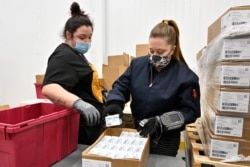 Employees with the McKesson Corporation scan a box of the Johnson & Johnson COVID-19 vaccine while filling an order at their shipping facility in Shepherdsville, Kentucky, March 1, 2021.
