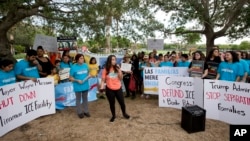 Camila Duarte, center, of Venezuela, speaks in front of the Immigration and Customs Enforcement offices, June 1, 2018, in Miramar, Fla. The demonstration was part on the Families Belong Together Day of Action, where demonstrators in cities across the U.S.