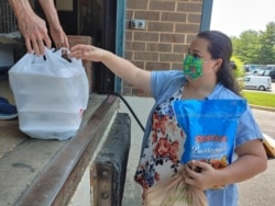 Mandy Recinos picks up provisions for her family at Food for Others in Fairfax, Virginia, the largest food pantry in northern Virginia, June 14, 2021. (Deborah Block/VOA)
