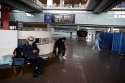 People wearing face masks look at their cellphones at Beijing Capital International Airport, as the country is hit by an outbreak of the novel coronavirus, in Beijing, China March 16, 2020.
