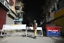 An Indian paramilitary trooper stands guard at a roadblock at Maisuma locality in Srinagar, Aug. 4, 2019.