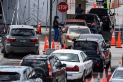 A medical staff member assists people in their cars at a rapid antigen coronavirus testing site at Hard Rock Stadium in Miami Gardens near Miami, Aug. 5, 2020.
