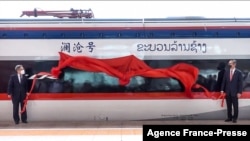 This frame grab from Lao National TV video footage taken Oct. 16, 2021, via AFPTV shows Laos' Minister of Public Works and Transport Viengsavath Siphandone (R) and China's Ambassador to Laos Jiang Zaidong unveiling a sign for a high-speed rail line in Vientiane, Laos.