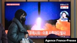 A woman walks past a television screen showing a news broadcast with file footage of a North Korean missile test, at a railway station in Seoul on Jan. 17, 2022.