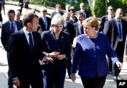 FILE - German Chancellor Angela Merkel, right, speaks with French President Emmanuel Macron, left, and British Prime Minister Theresa May after meeting at a hotel on the sidelines of an EU-Western Balkans summit in Sofia, Bulgaria, May 17, 2018.