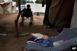 FILE - Fifteen-year-old Ahmed Khalil Isa, a disabled Syrian teenager, sits in his wheelchair outside his family's tent at the Ritsona refugee camp north of Athensm, Greece, Sept. 19, 2016.