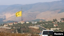 FILE - A U.N. peacekeepers (UNIFIL) vehicle drives past a Hezbollah flag in the southern Lebanese village of Khiam, near the border with Israel, July 28, 2020.