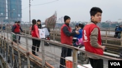 Members of environmental group The Carp Team encourage passing motorbike drivers on Long Bien Bridge not to drop plastic bags, Hanoi, February 12, 2014. (Marianne Brown for VOA News)