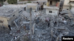 FILE - Residents inspect a damaged site from what activists said were airstrikes carried out by the Russian air force in Nawa city, Deraa, Syria, Nov. 21, 2015.