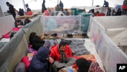 Migrants sit in a temporary shelter at the Lipa camp northwestern Bosnia, Dec. 26, 2020, where hundreds of migrants are stranded in a burned-out, squalid camp in Bosnia as heavy snow fell in the country and temperatures dropped.