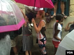 Cubans stand in the rain, hoping to catch a glimpse of U.S. President Barack Obama, after he arrived in Havana, Cuba, March 20, 2016. (V. Macchi / VOA )