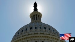 FILE - The US flag flies next to the Capitol in Washington, as Congress and the Obama Administration continue work to open the government and raise the debt ceiling.