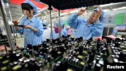 FILE - Employees are seen working on a FiberHome Technologies Group factory production line in Wuhan, Hubei province, China, July 27, 2015.