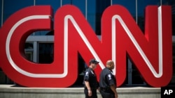 FILE - Security guards walk past the entrance to CNN headquarters in Atlanta. 